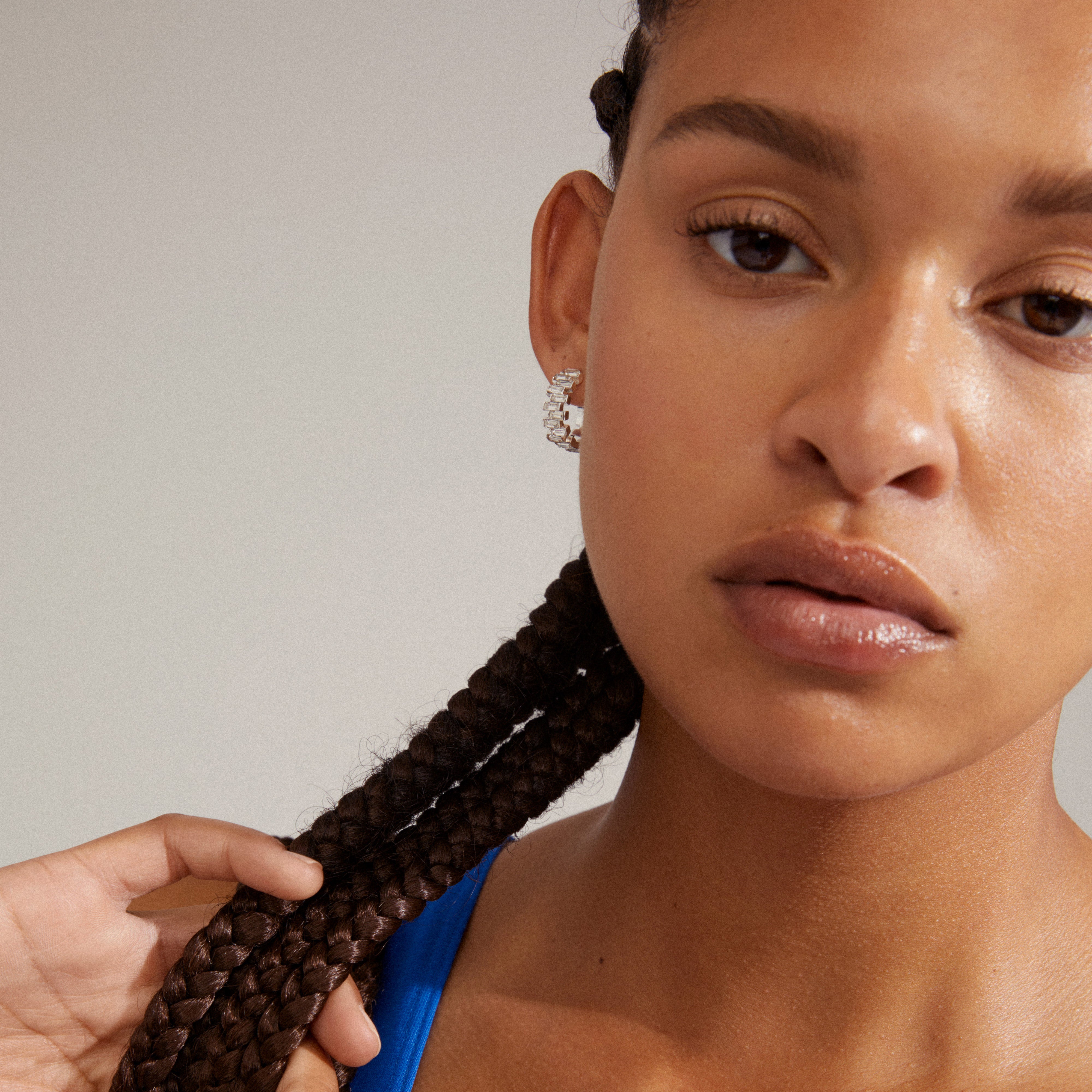 HELI crystal hoop earrings silver-plated, worn by a woman with braids, featuring staggered light crystal stones and a classy, eye-catching structure.