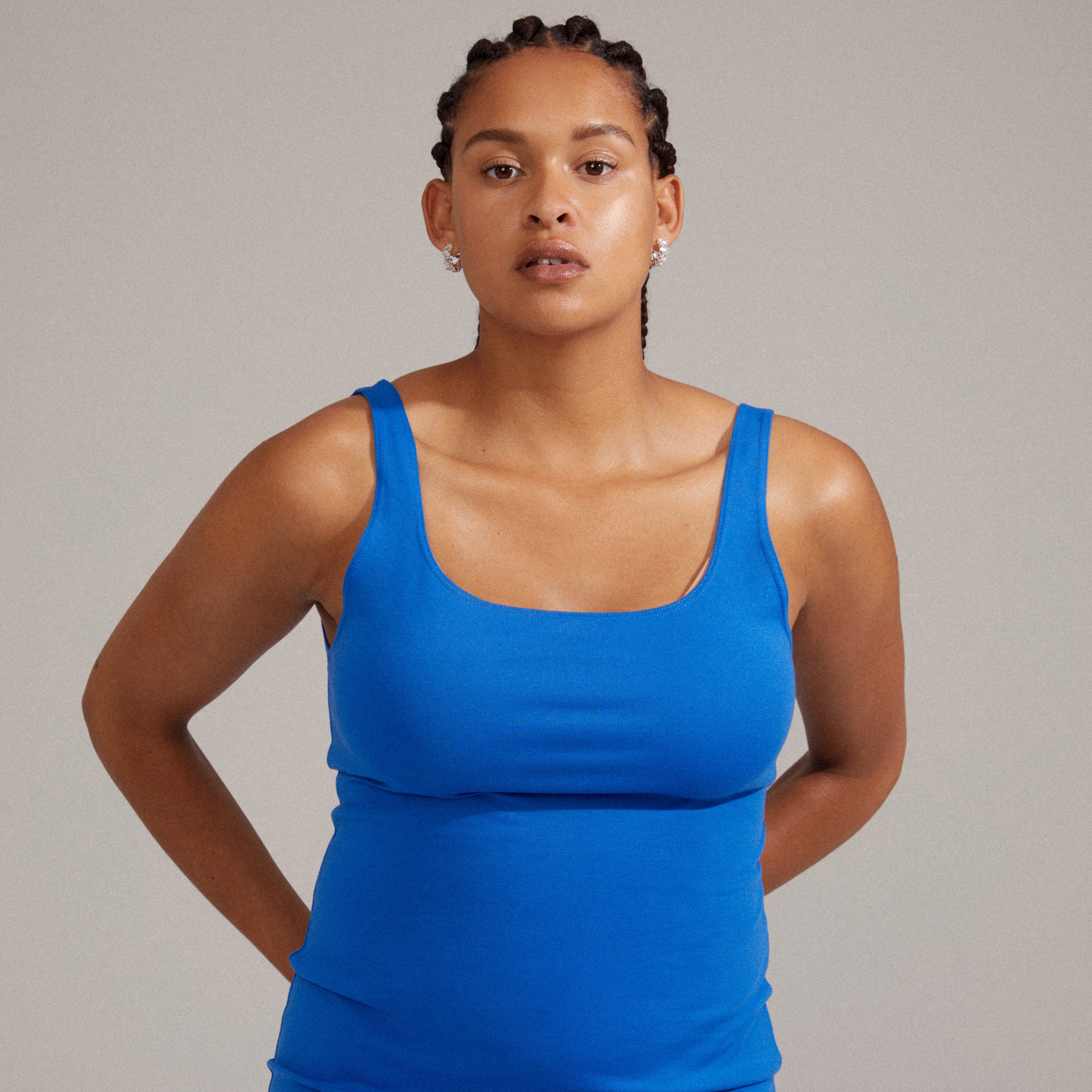 HELI crystal hoop earrings silver-plated, featuring staggered light crystal stones, shown worn by a woman in a blue tank top, showcasing their elegant design.