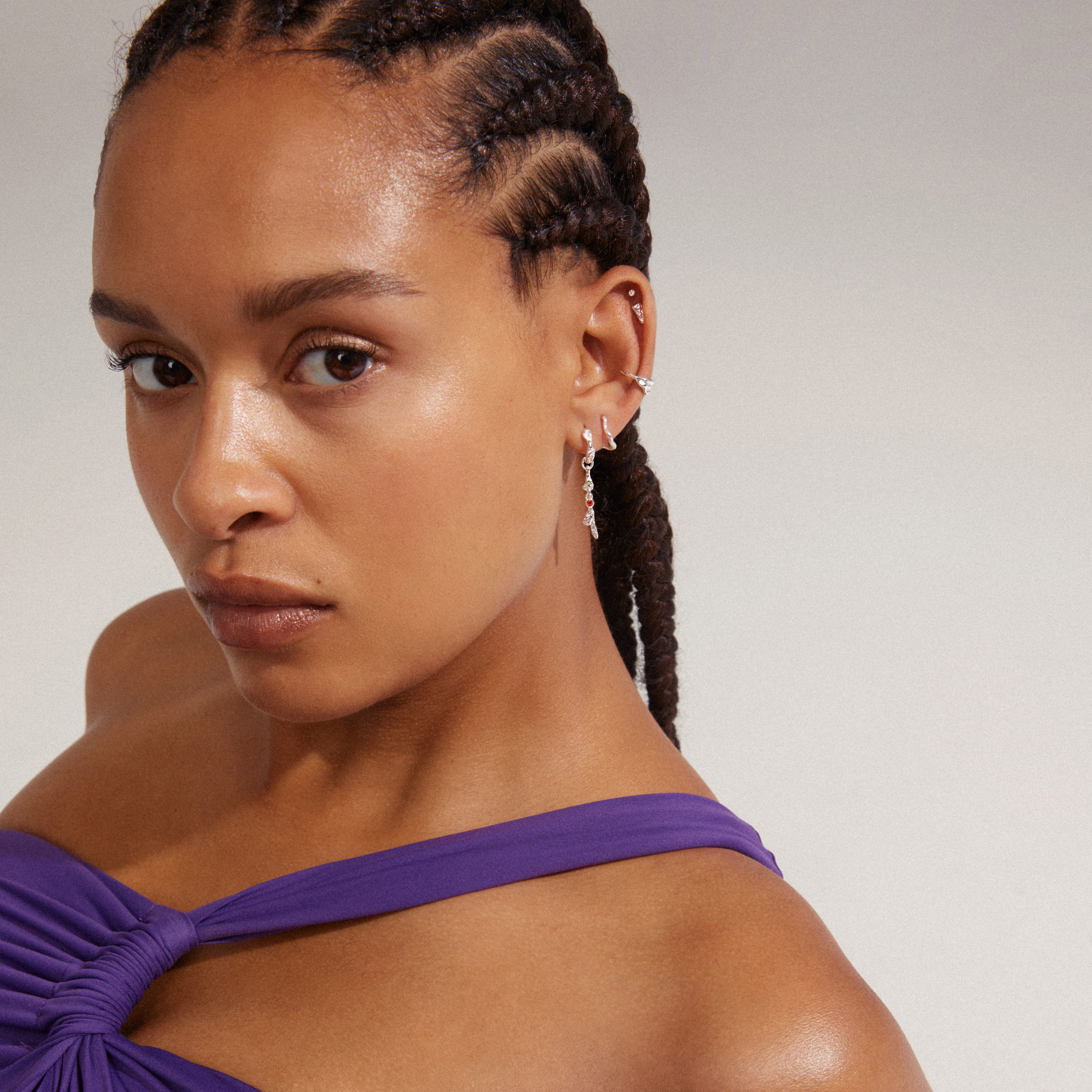 Close-up of a woman wearing Pilgrim's IRENE silver-plated 5-in-1 earrings set, highlighting asymmetrical designs including studs, huggie hoop, and ear cuff.