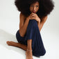 Woman with afro hair models the silver-plated SLOAN ankle chain by Pilgrim, featuring white freshwater pearls and glass beads for a romantic, handcrafted look.