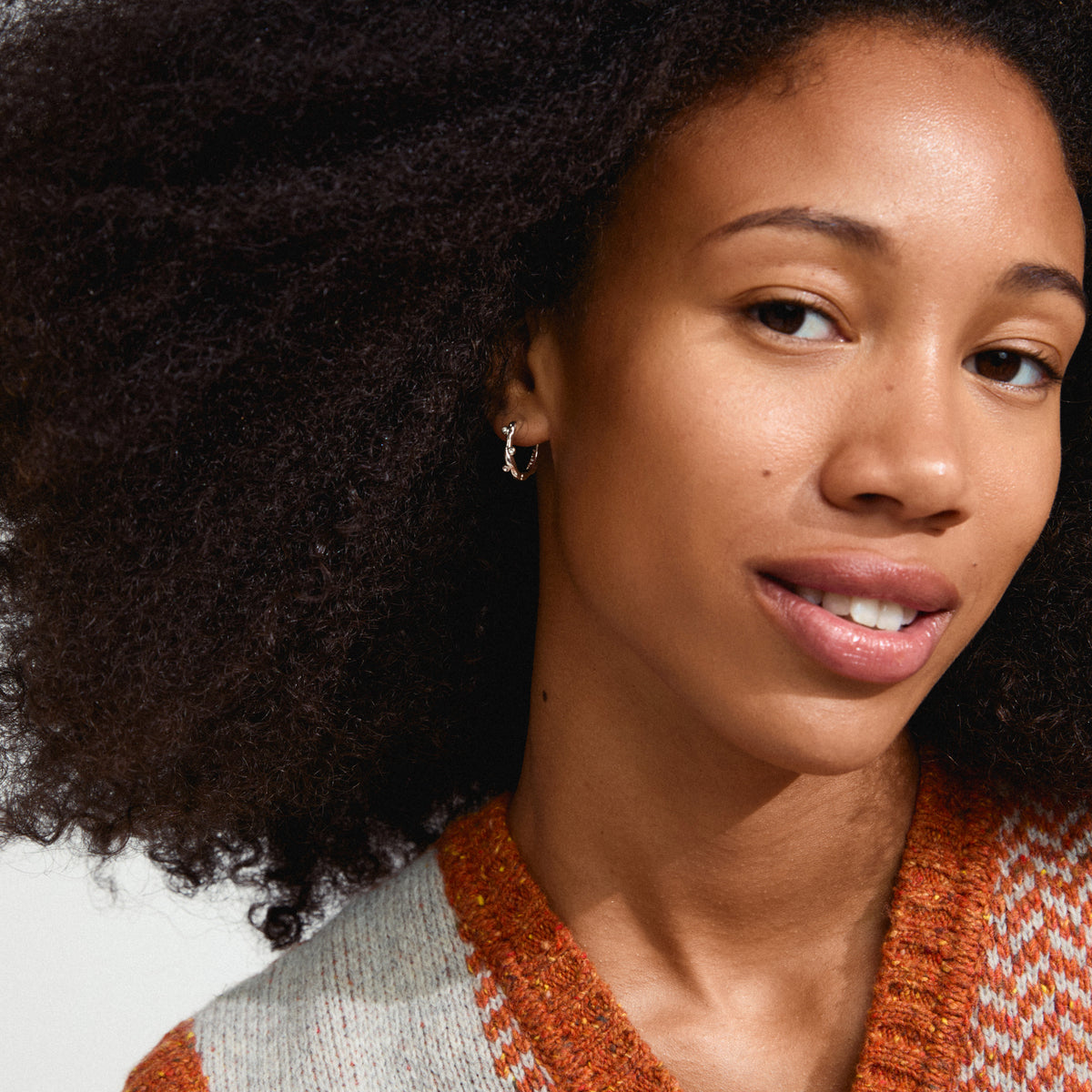 HERMIONE earrings silver-plated on a woman with curly hair, showcasing their organic shape and sparkling Preciosa crystals, embodying Pilgrim's handmade Danish jewelry style.