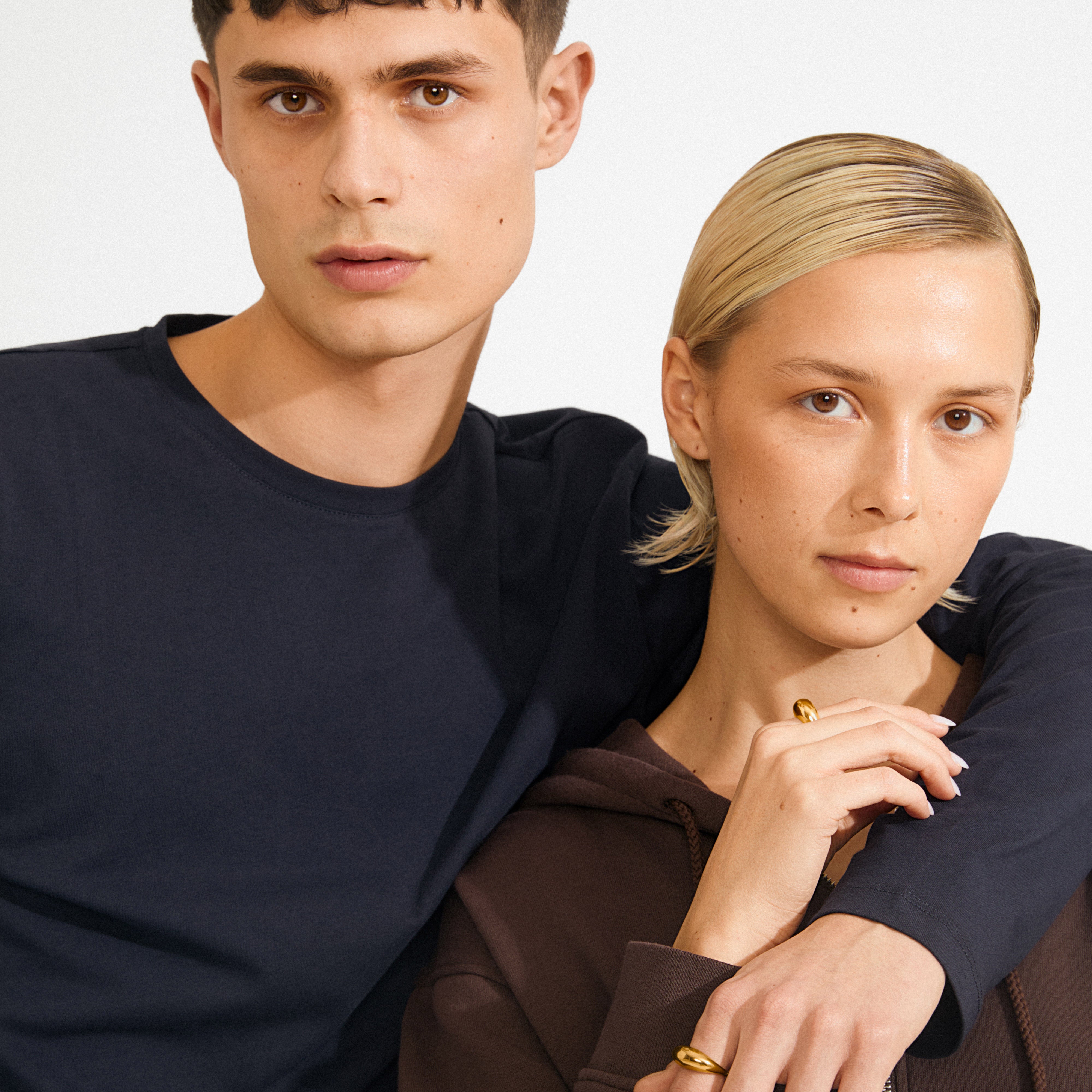 Young woman showcases the gold-plated BRAXTYN ring from Pilgrim, highlighting its chunky, minimalist design as she gently touches her face.