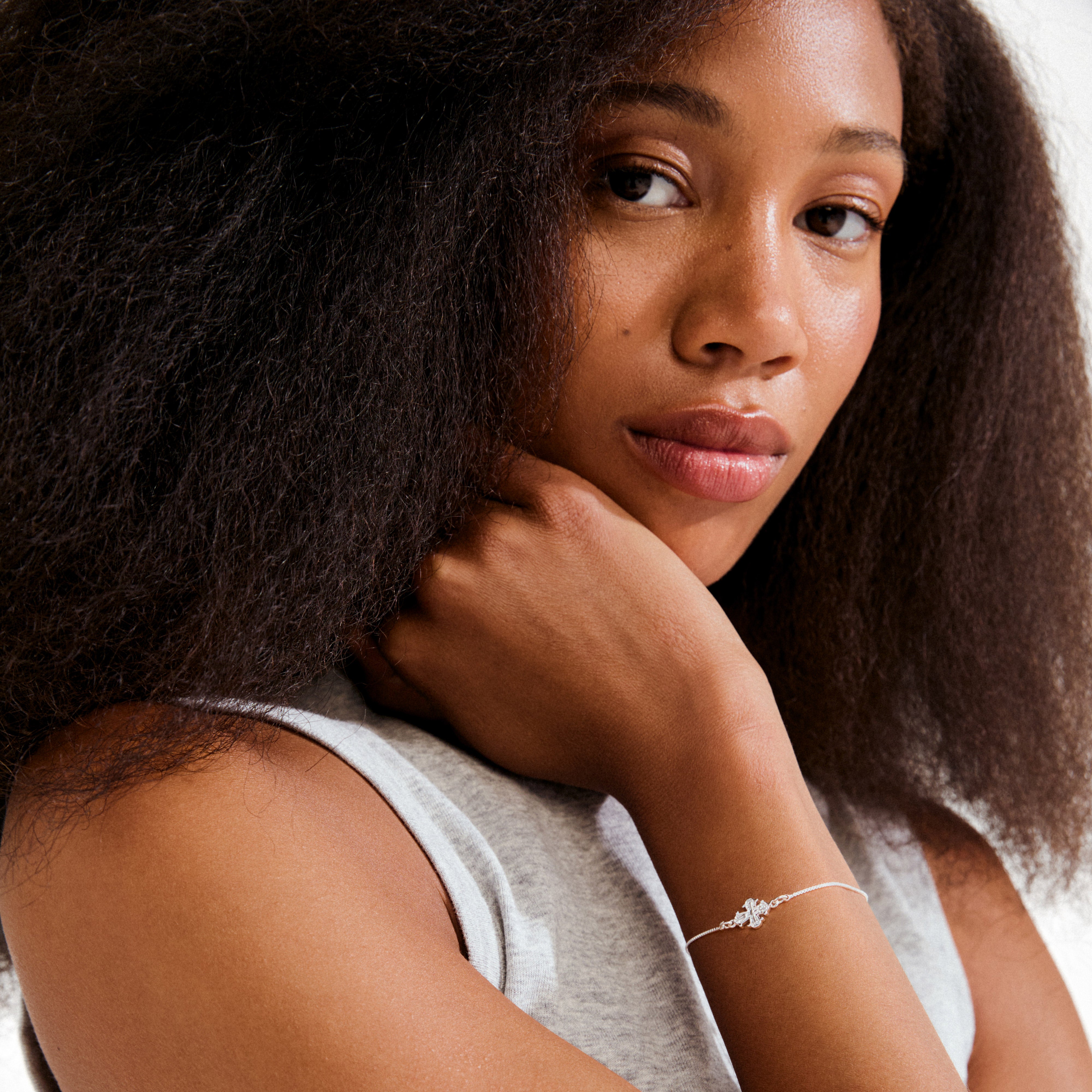 Young woman wearing Pilgrim's DAGMAR bracelet, featuring a silver-plated chain and cross charm, embodying timeless elegance and Scandinavian craftsmanship.