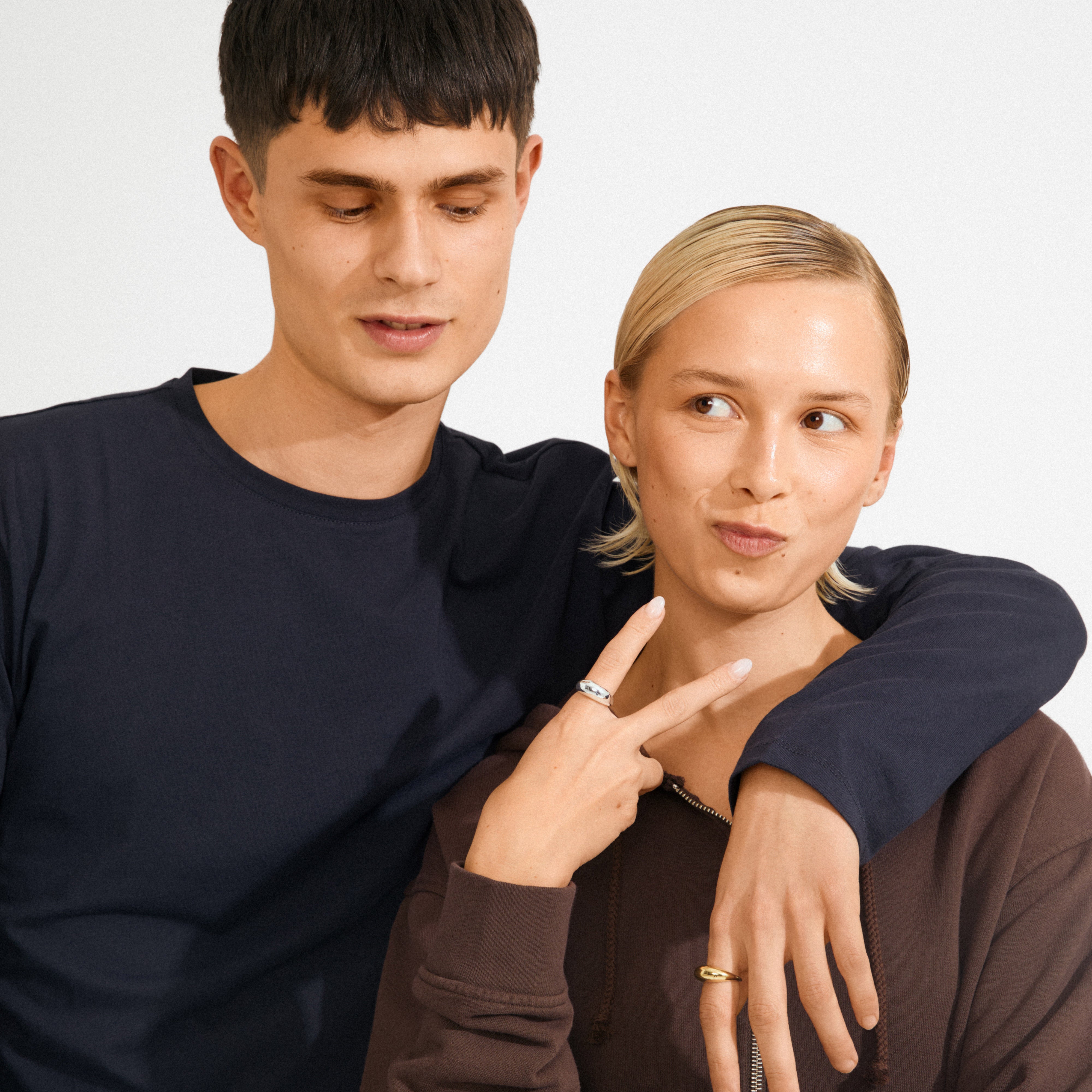 Two young adults showcase the BRAXTYN silver-plated ring by Pilgrim, highlighting its sleek, adjustable design. The ring complements a casual, friendly style.
