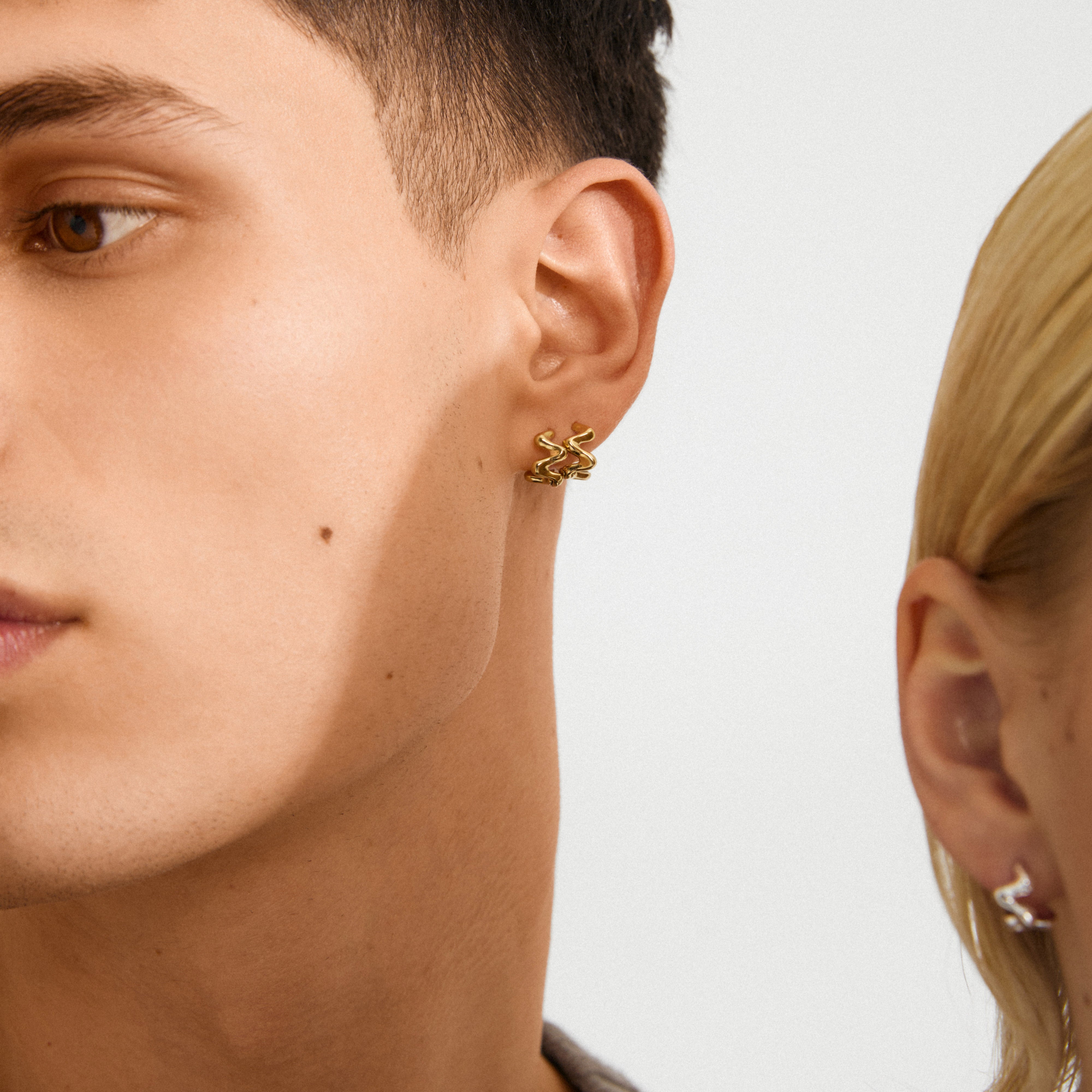 Close-up of a young man and woman wearing AIKO silver-plated squiggly earrings, showcasing edgy elegance and modern style from Pilgrim's recycled jewelry collection.