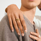 AIKO ring silver-plated showcased with a smooth, wavy design on a hand over a shoulder, highlighting its sculptural elegance and textured knit fabric contrast.