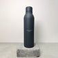 Recycled steel bottle 470 ml - grey, black cylindrical design, resting on concrete block; insulated for maintaining drink temperature.
