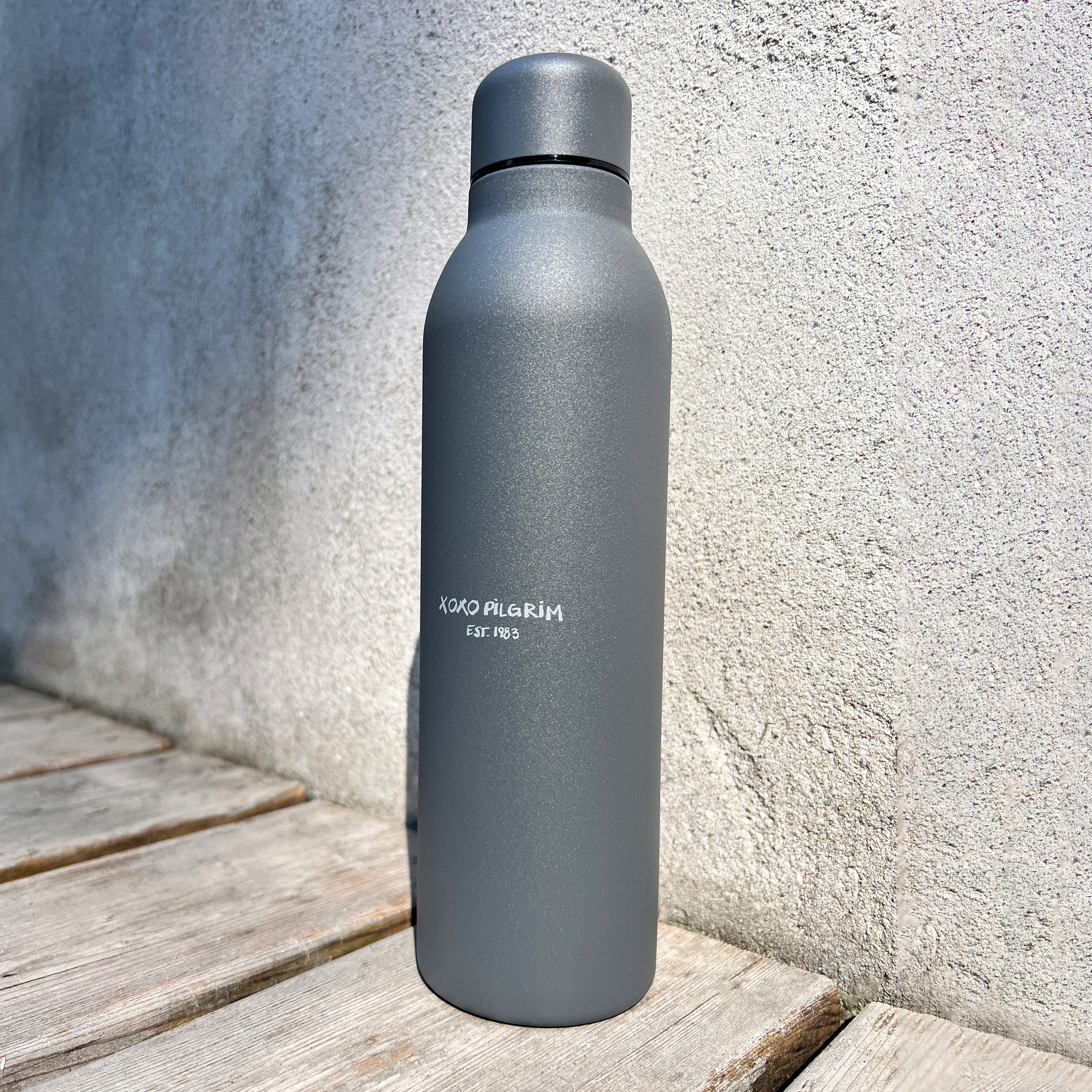 Recycled steel bottle 470 ml - grey, on a wooden surface. Features a matte finish and vacuum insulation, ideal for maintaining drink temperature.