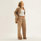 Woman in oversized white organic cotton PILGRIM PJ set XS/S, featuring loose-fit pants and a shirt, showcasing relaxed, genderless loungewear style.