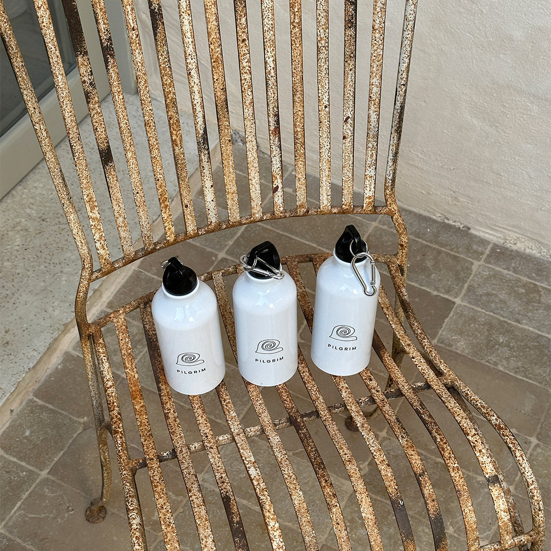 White 400 ml aluminium bottle featuring Pilgrim logo, minimalist design, with a practical carabiner for easy attachment, ideal for on-the-go hydration.