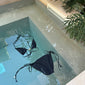 Black bikini XS/S with triangle top, chunky beads, and high-cut bottoms featuring side ties. Comes in a sleek black pouch, ideal for beach days.