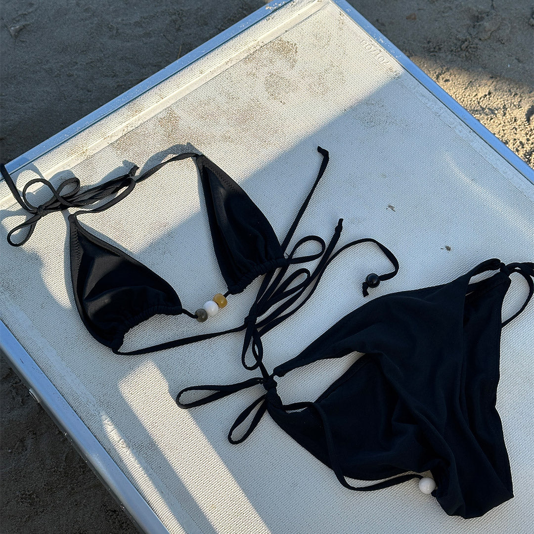 Black bikini, XS/S, featuring a triangle top with earthy chunky beads, high-cut bottoms with side ties, and decorative boho straps from Pilgrim.