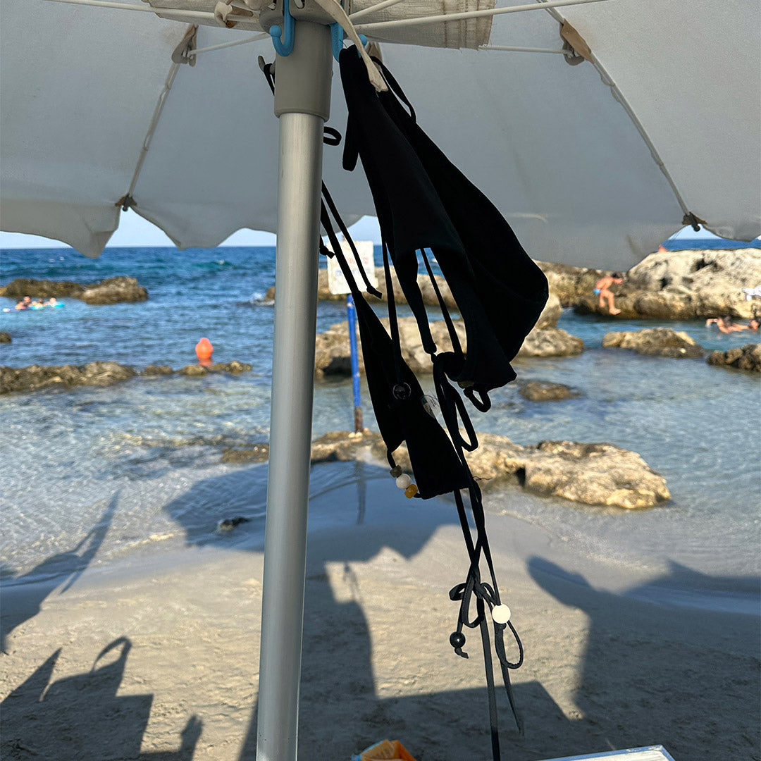 Black triangle bikini with chunky beaded halter neck and high-cut bottoms, featuring decorative straps and side ties, in size M/L.