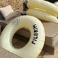 Off-white swim ring with black Pilgrim logo, 120 cm diameter, perfect for poolside relaxation or beach lounging.