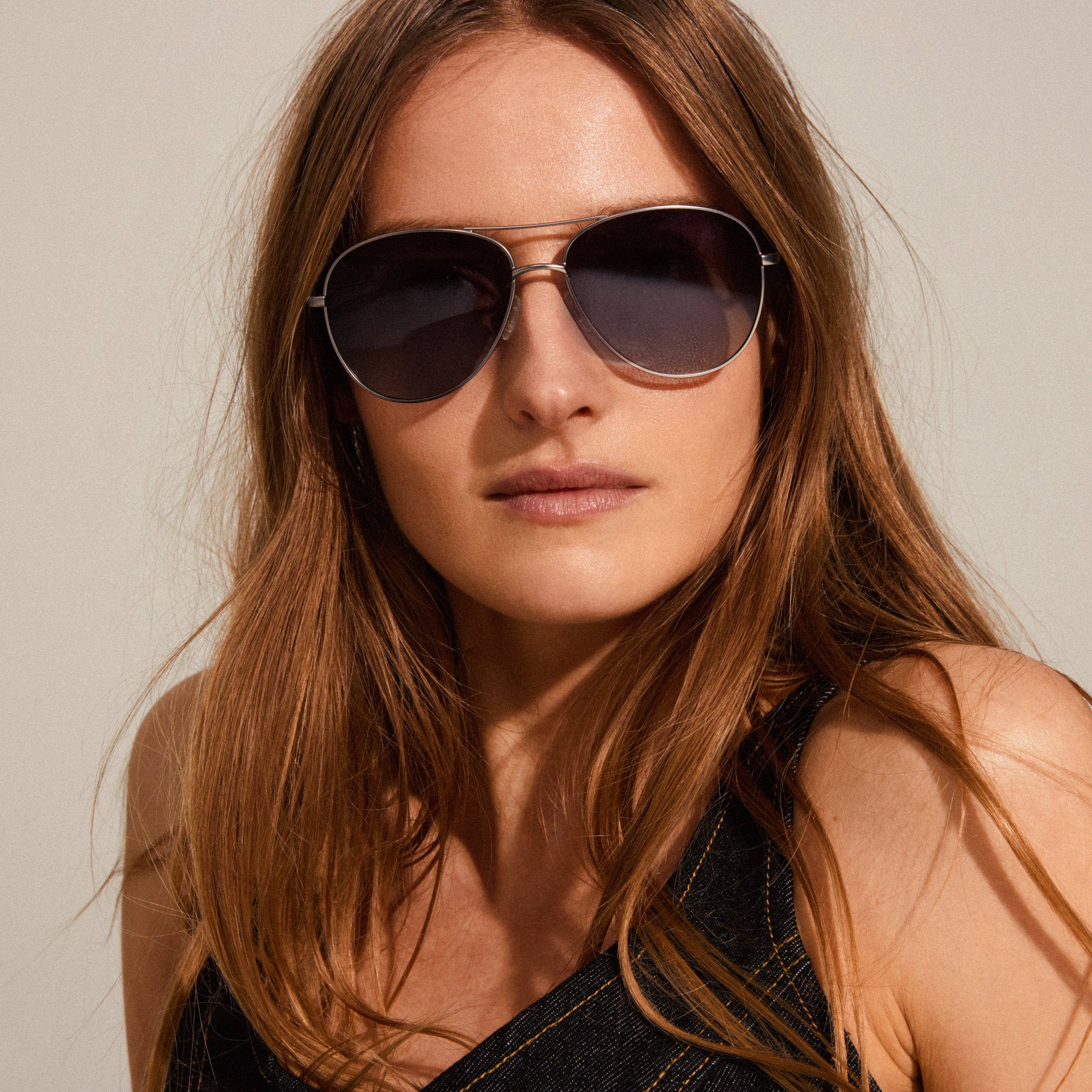 NANI pilot sunglasses with bluish lenses and silver-plated frame on a woman, showcasing their avant-garde style and 70s-inspired design.