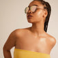 NANI pilot sunglasses in pink/gold with a 70s-inspired pilot style and rose gold frame, worn by a woman looking away.