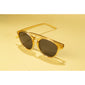 VASILIA sunglasses with a transparent frame and dark lenses on a yellow surface, embodying a trendy, feminine style with UVA/UVB protection.