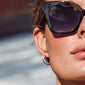 Woman wearing Pilgrim's Dael sunglasses, showcasing an ultra chunky butterfly-shaped frame, embodying retro coolness with UVA/UVB protection and polarized lenses.