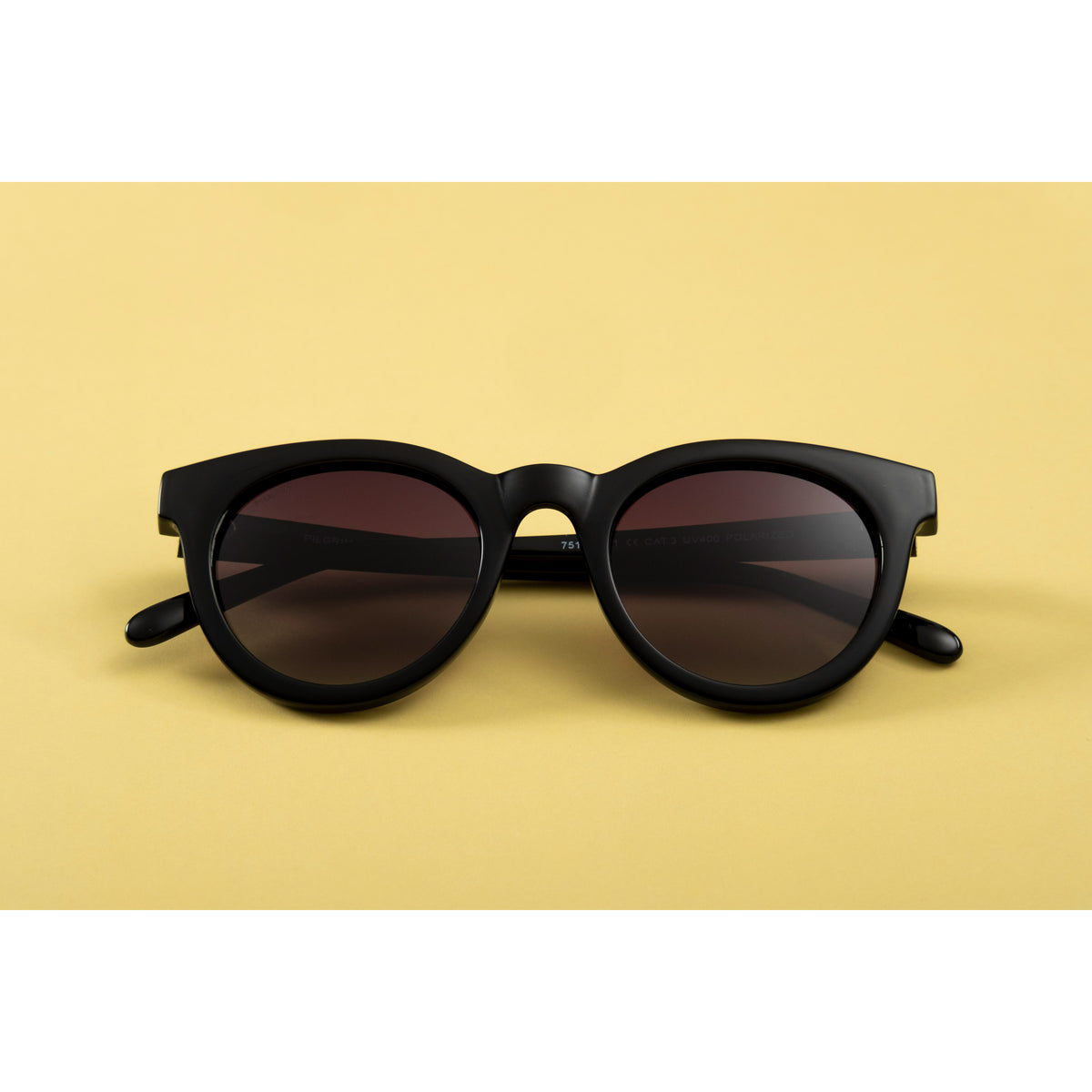 Sunglasses: Meriel: Black - Classic round sunglasses with black frames, brown lenses, and metal temple detail, offering stylish sun protection.