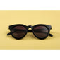 Sunglasses: Meriel: Black - Classic round sunglasses with black frames, brown lenses, and metal temple detail, offering stylish sun protection.