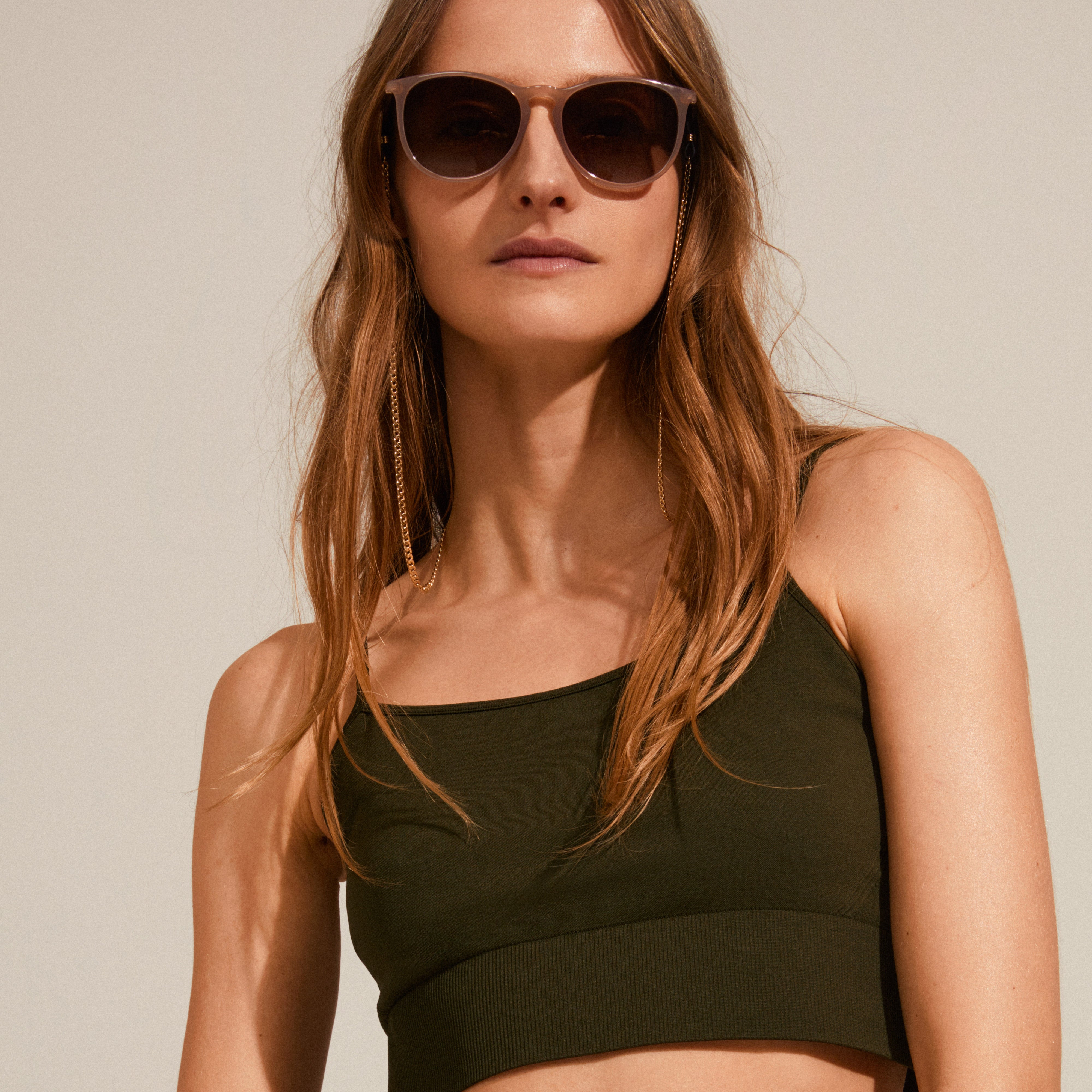 Woman wearing sunglasses with AJA curb chain for sunglasses, gold-plated, enhancing her stylish look with a trendy and functional accessory.