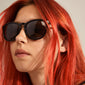 CAMILLA light frame sunglasses black, featuring a classic design made from recycled ocean plastic, worn by a woman with red hair and sunglasses.