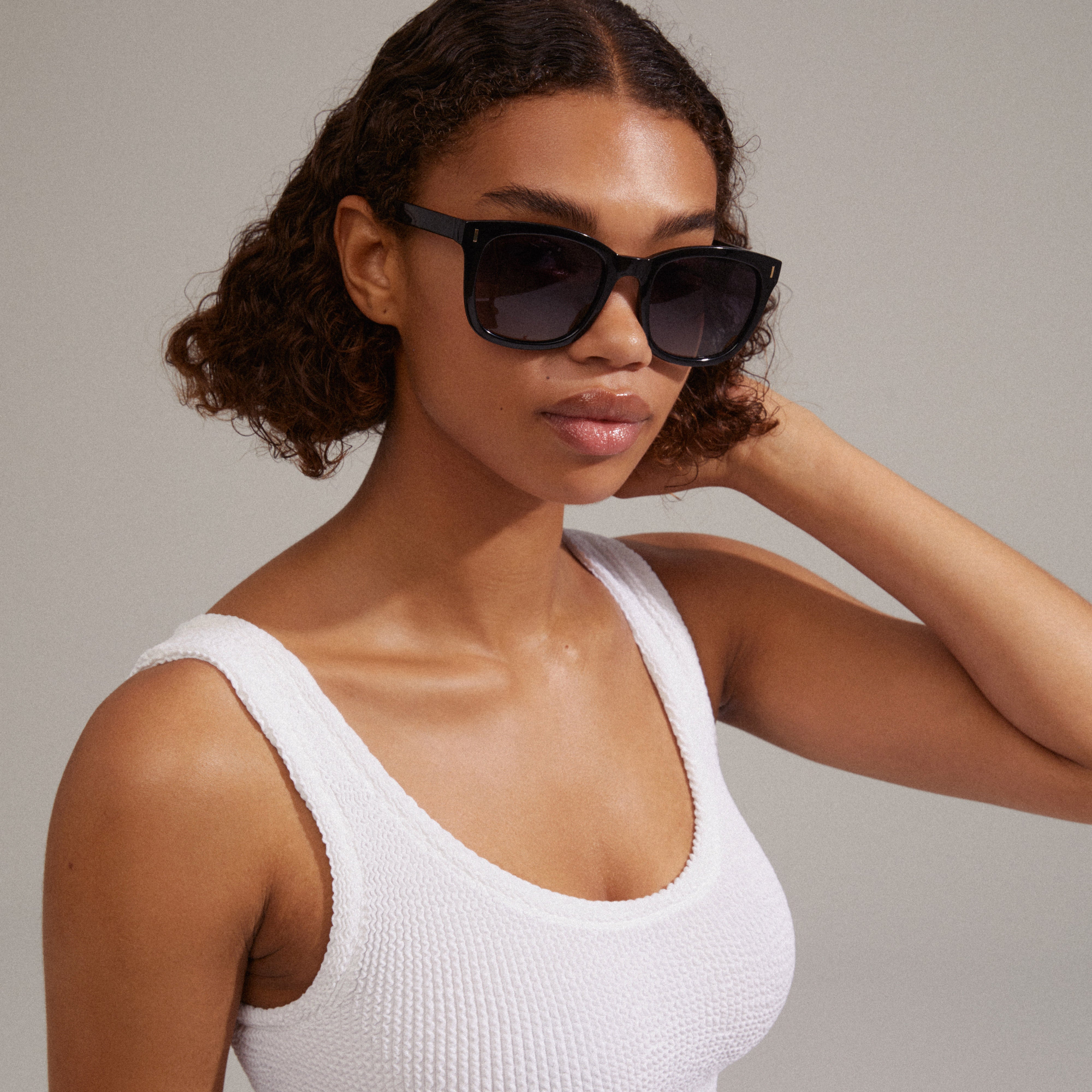 KATYA iconic retro sunglasses black, worn by a woman, featuring recycled materials with silver accents, ideal for both beachwear and casual outfits.