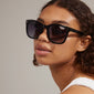 KATYA iconic retro sunglasses in black, worn by a woman, featuring a sleek silver detail, embodying classic style and sustainable fashion with UV400 protection.