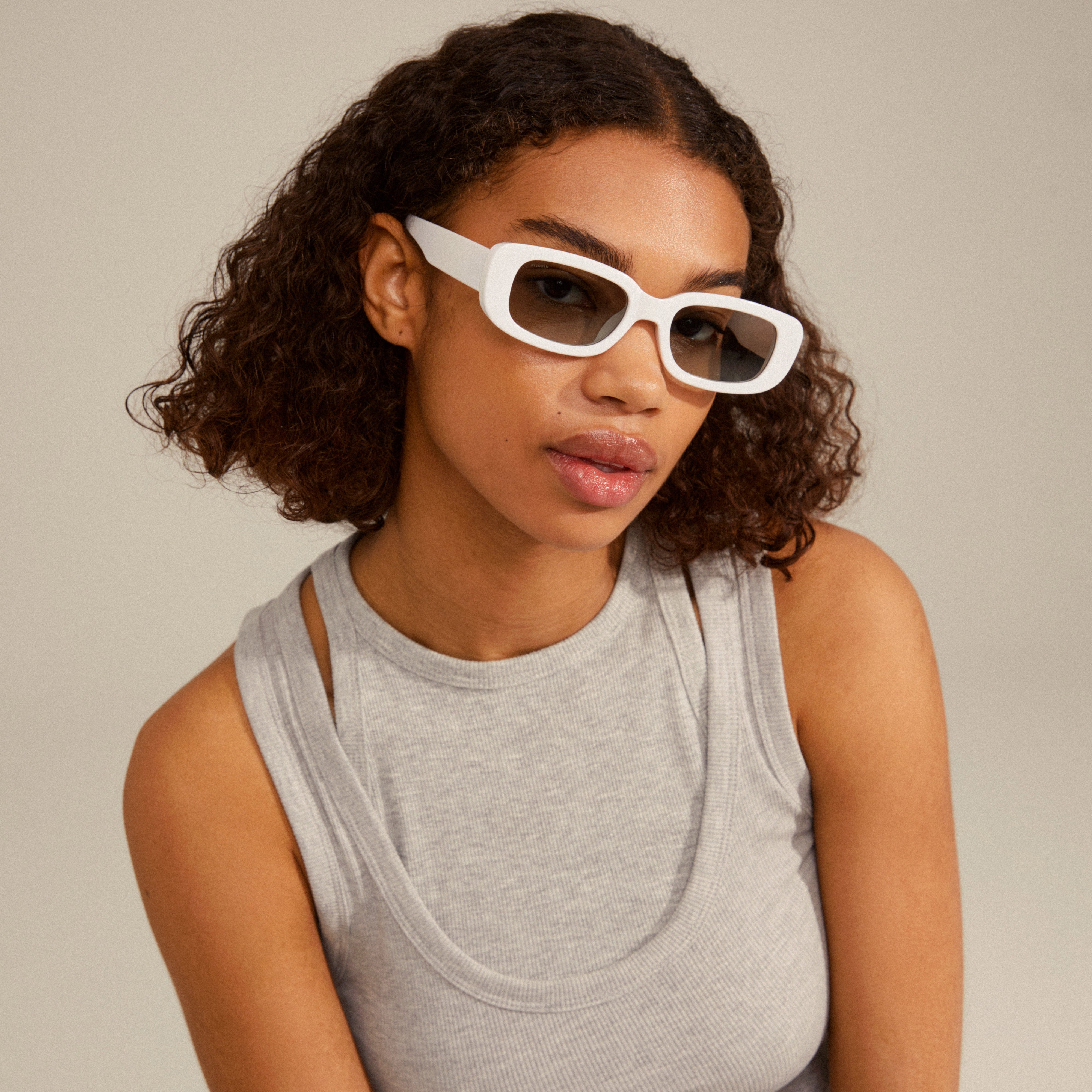 Woman wearing YANSEL white sunglasses from Pilgrim, showcasing a bold, vintage-inspired design with square frames, offering UV protection and sustainability. Ideal for trendsetters.