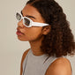 Woman wearing YANSEL white sunglasses, featuring a chunky, vintage-inspired square design. Perfect for trendsetters, made from recycled plastic with UVA/UVB protection.