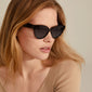 Woman wearing RAISA sunglasses black, cat-eye style from Pilgrim, showcasing elegance and versatility with UVA/UVB protection and sustainable materials.