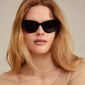 Woman wearing black RAISA sunglasses by Pilgrim, featuring a timeless cat-eye shape and UVA/UVB protection, highlighting elegance and style.