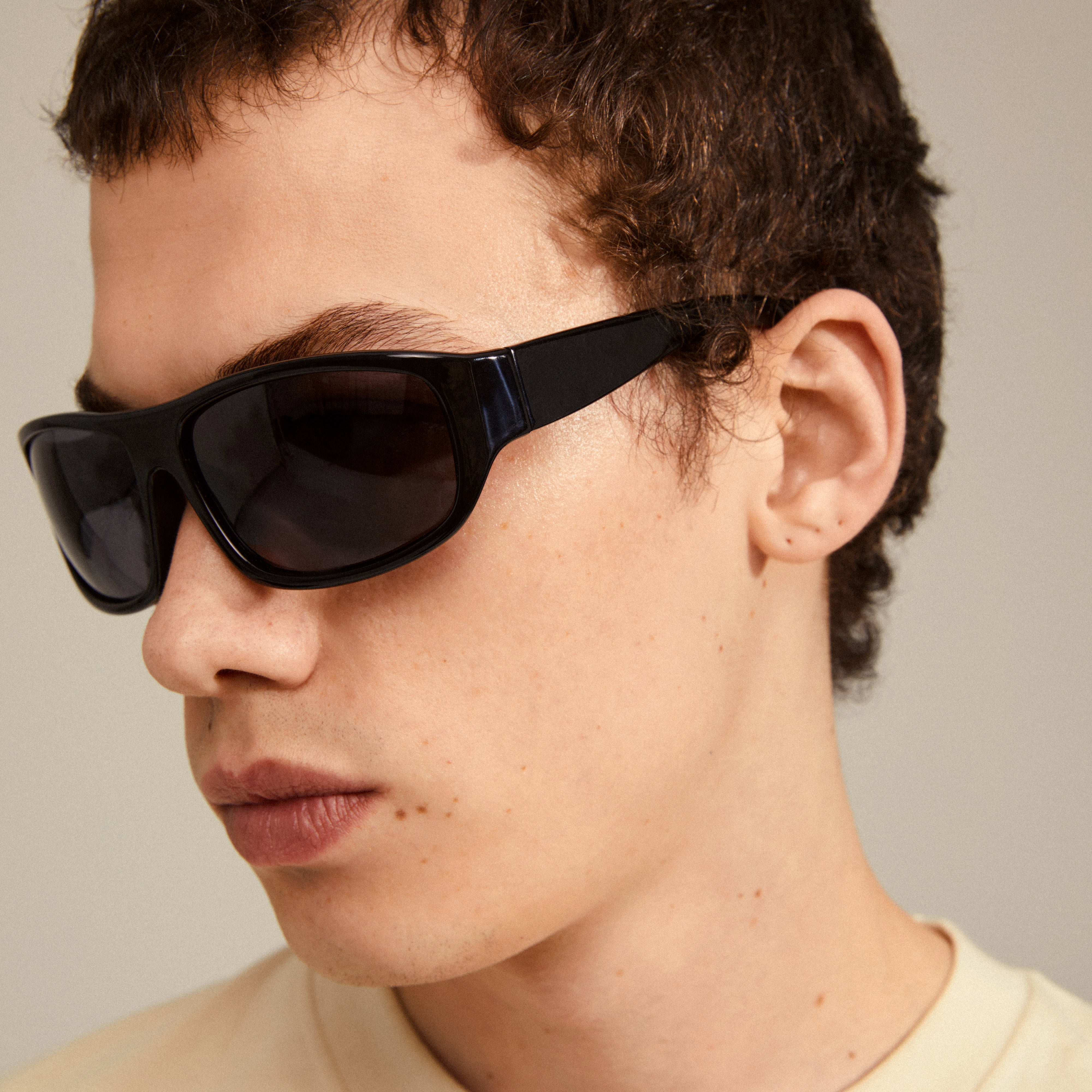 GERTRUD sunglasses black worn by a man, showcasing the sleek arched frames, combining classic design with modern edge. Ideal for style-conscious individuals.