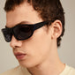 GERTRUD sunglasses black worn by a man, showcasing the sleek arched frames, combining classic design with modern edge. Ideal for style-conscious individuals.