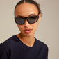 GERTRUD sunglasses black from Pilgrim, featuring a classic yet edgy design with arched frames, worn by a woman, offering UVA/UVB protection.