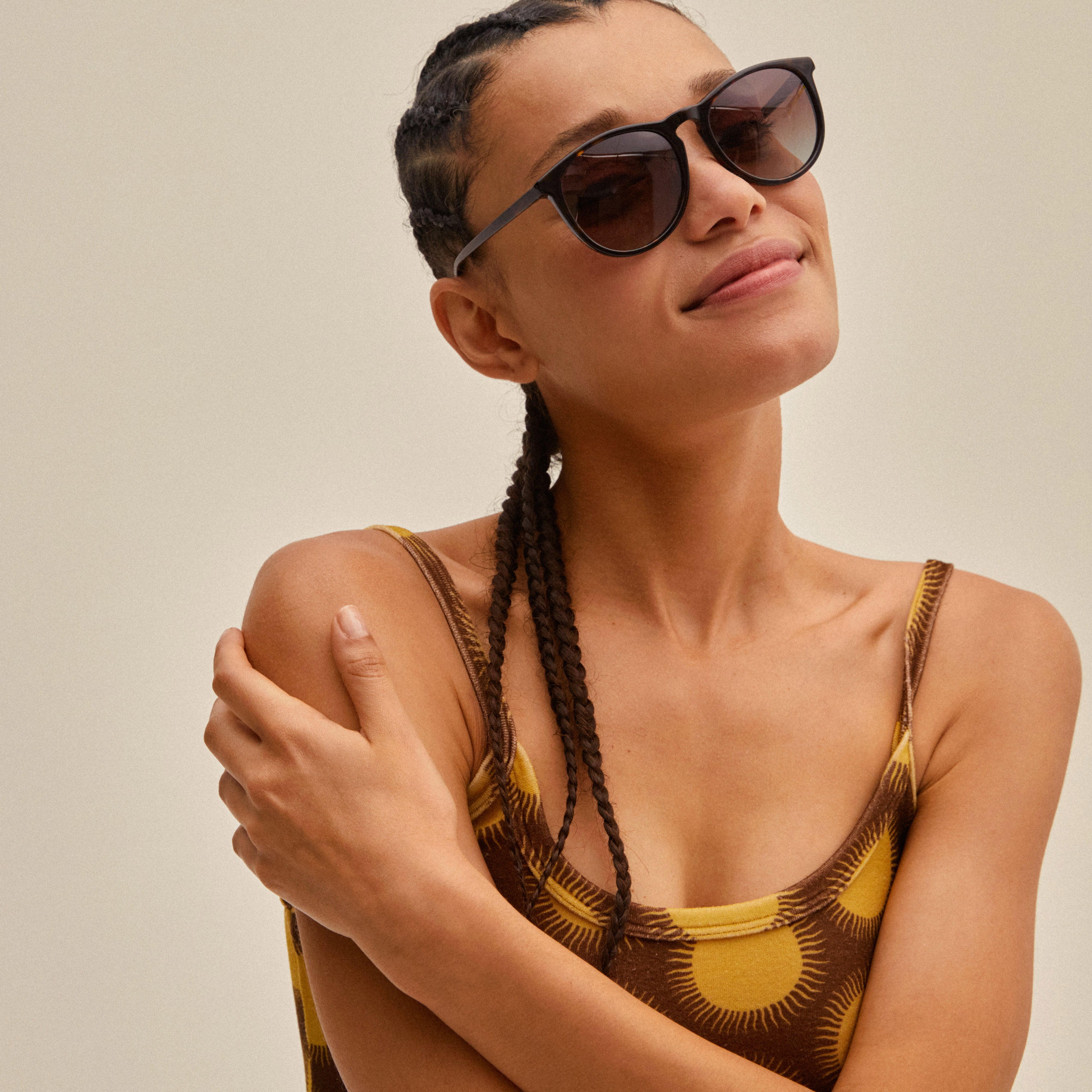 Woman with braids wears tortoise brown SAHARA sunglasses, embodying modern style. The eyewear features recycled acetate and offers complete UV protection.