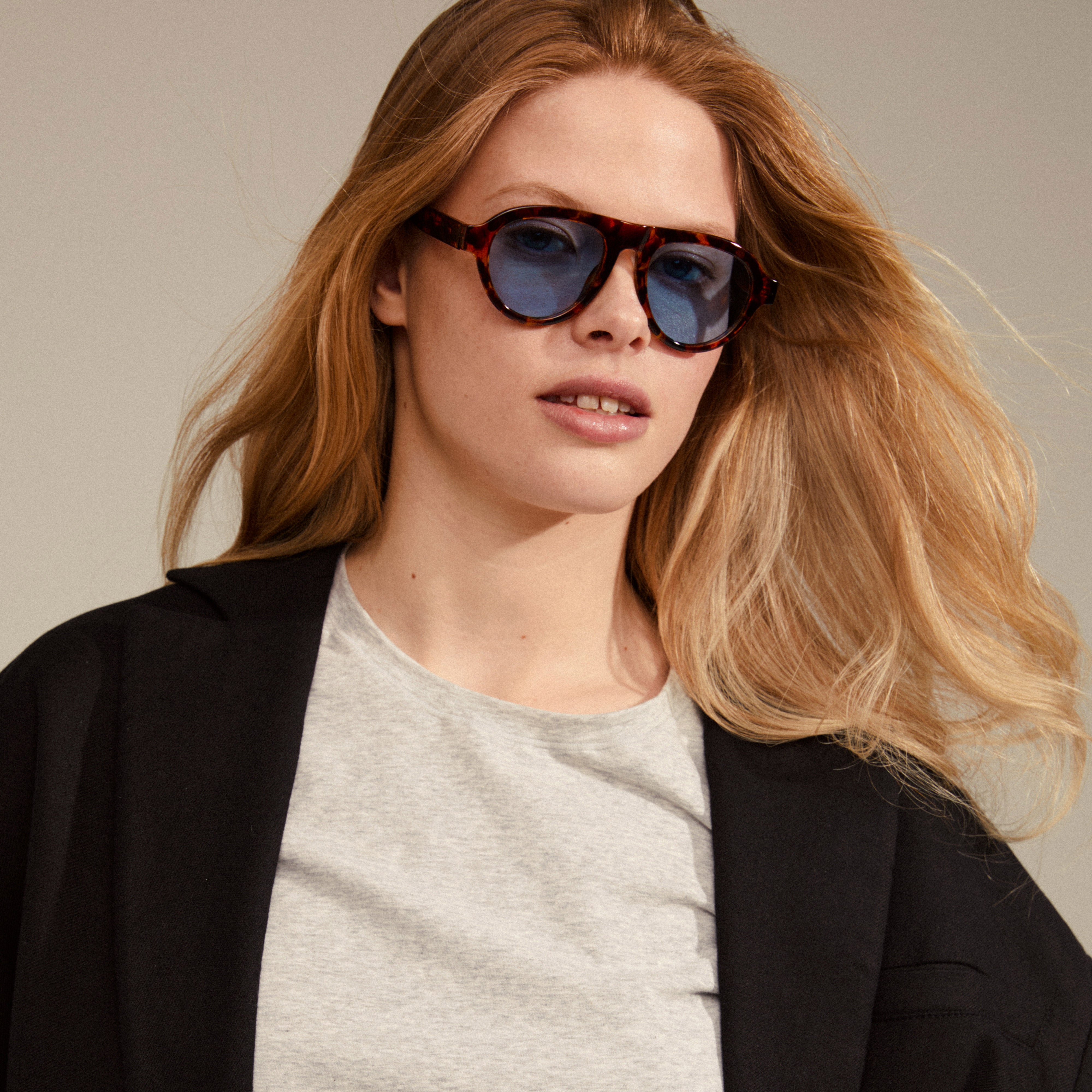 YARIL sunglasses in tortoise brown, worn by a woman, feature light blue lenses. A stylish accessory offering UVA/UVB protection, ideal for summer fashion.
