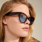 Woman wearing Pilgrim's RAISA sunglasses, featuring a timeless cat-eye shape, crafted from recycled plastic with UV400 protection, embodying elegance and sustainable fashion.