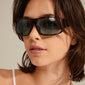 Woman wearing GERTRUD sunglasses in tortoise brown, showcasing their classic design with a trendy edge, featuring light blue lenses from Pilgrim.