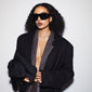 Woman wearing JOHARI sunglasses with oversized black frames and dark lenses, embodying trendy L.A. vibes, perfect for poolside or bar lounging.