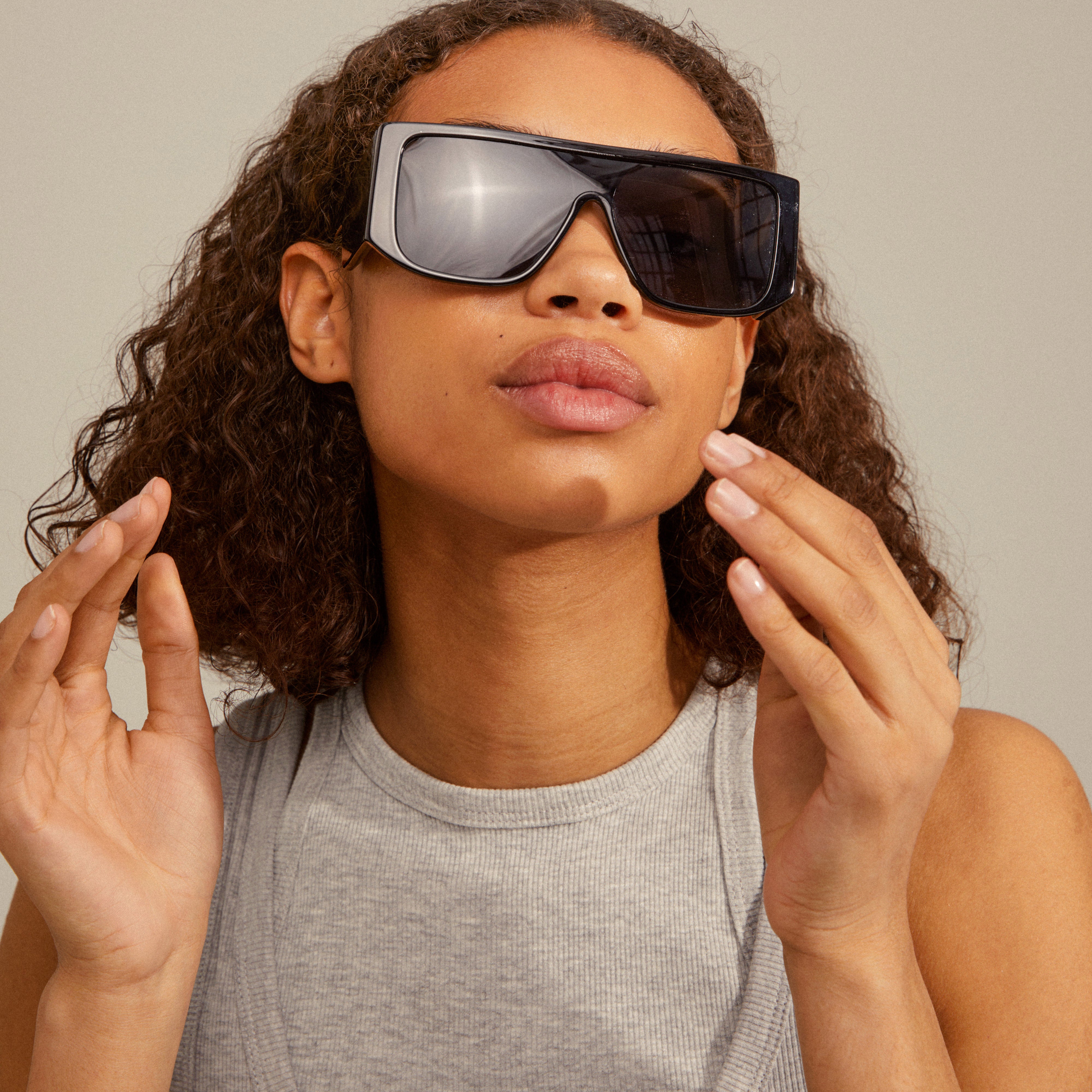 Woman modeling JOHARI sunglasses black, featuring oversized frames and broad temples, embodying trendy L.A. vibes with UVA/UVB protection.