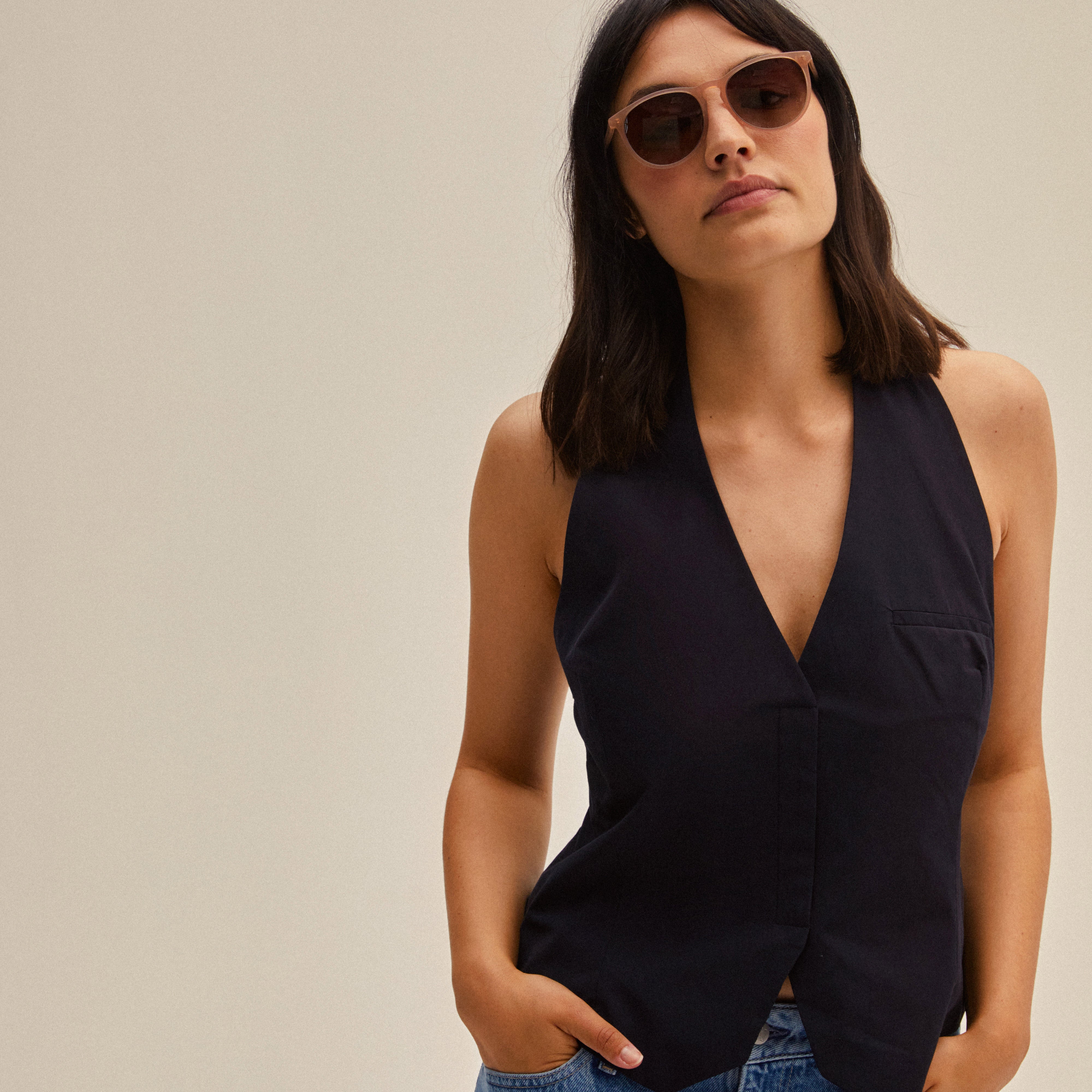 Woman wearing SAHARA sunglasses rose by Pilgrim, featuring slender frames made of recycled acetate, offering UVA/UVB protection and a sustainable pouch.