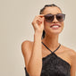 Woman smiling, wearing VANILLE sunglasses grey/gold by Pilgrim. Dark grey lenses, golden temples, stylish and versatile for any occasion.