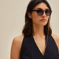 Woman wearing sunglasses with the PAOLA gold-plated chain for sunglasses, featuring a delicate cable-chain style, adding elegance to her look.