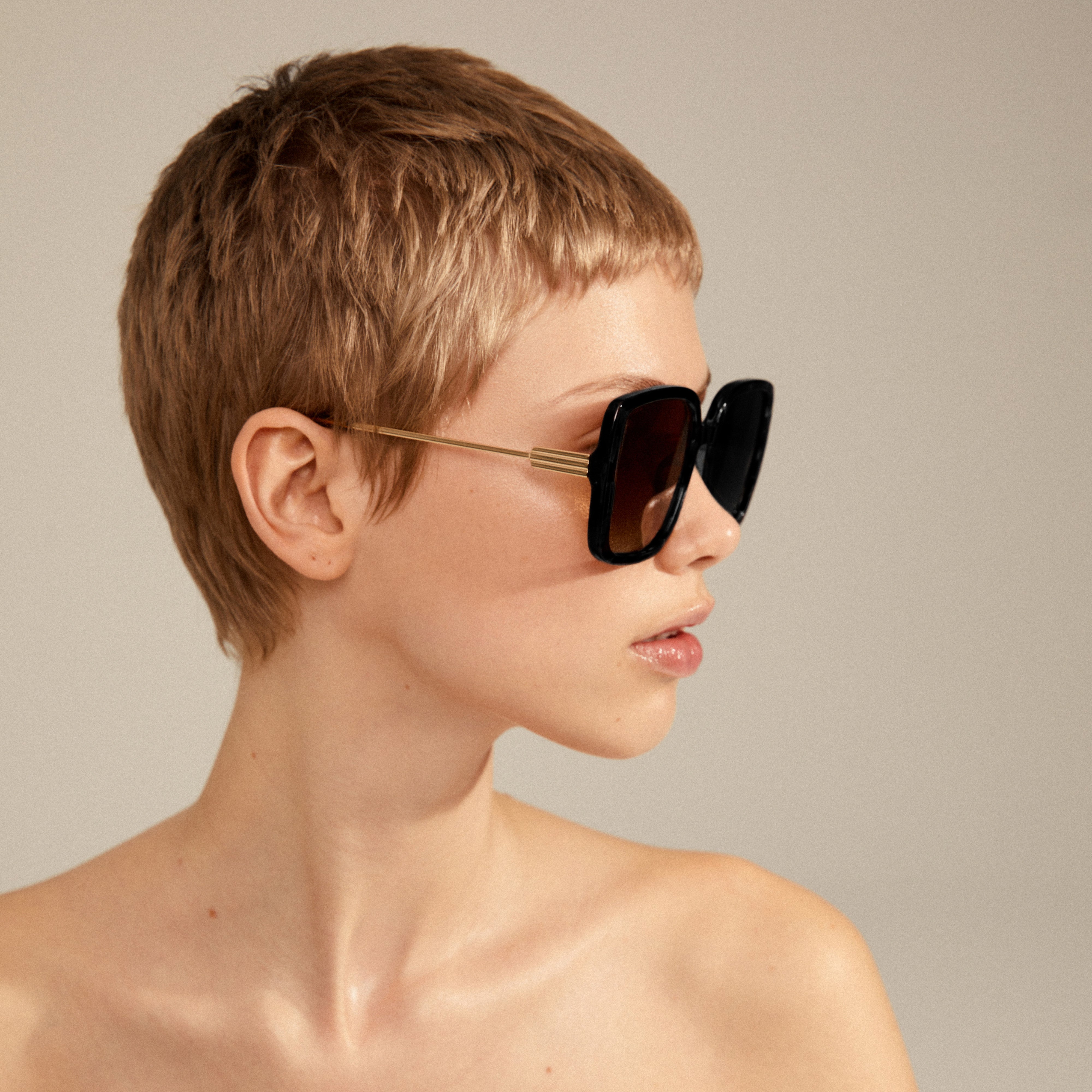 Woman with short hair wearing Pilgrim's ALIET sunglasses, showcasing their oversized, vintage-inspired design.