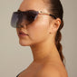 ALIAN sunglasses black/gold: Woman wearing sleek, futuristic single lens sunglasses with graded smoky glass, embodying urban style. Perfect for trendsetters seeking empowerment and style.
