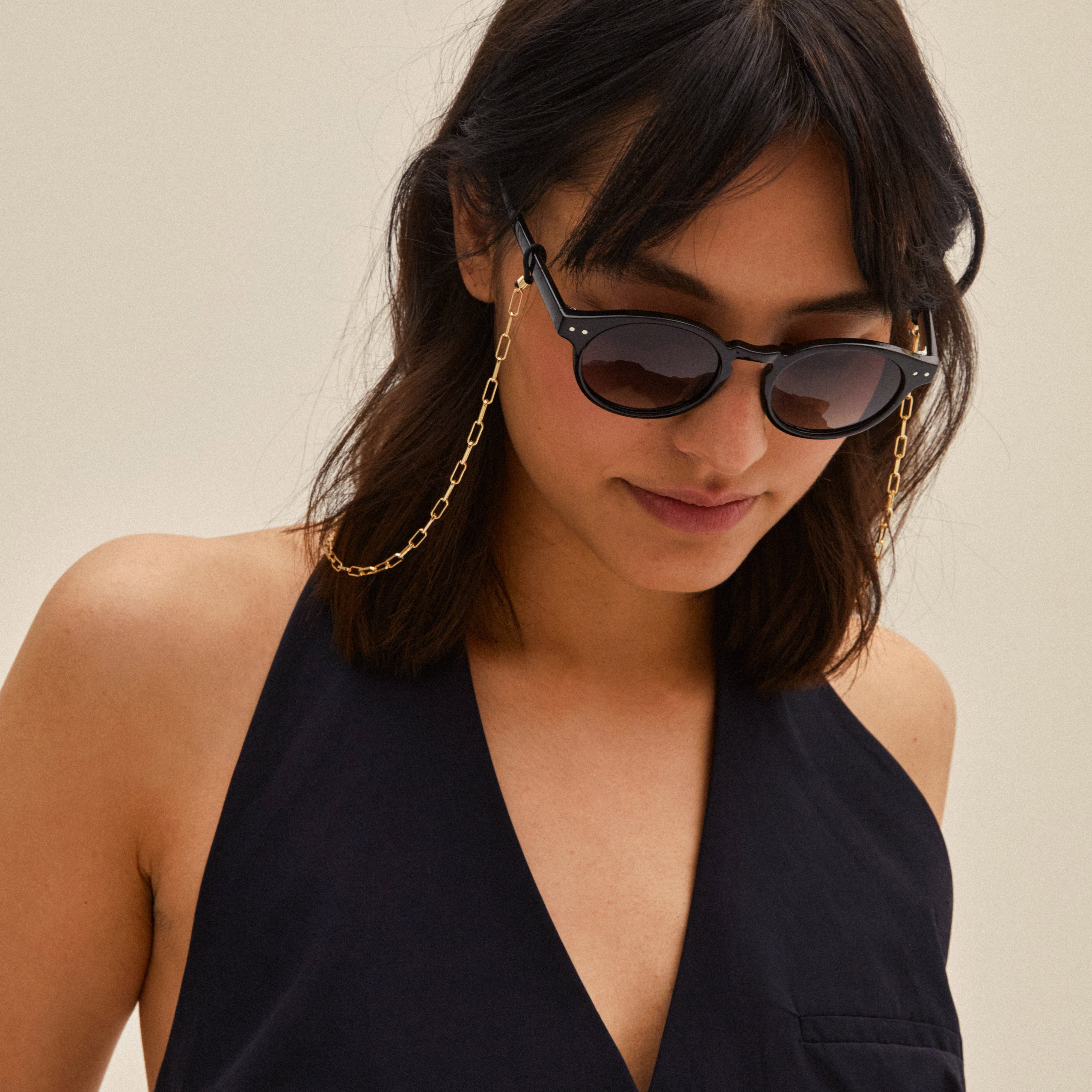 Woman wearing Pilgrim's KYRIE sunglasses in black/gold, showcasing round frames with a bold style and UV protection, highlighting Scandinavian design and trendiness.