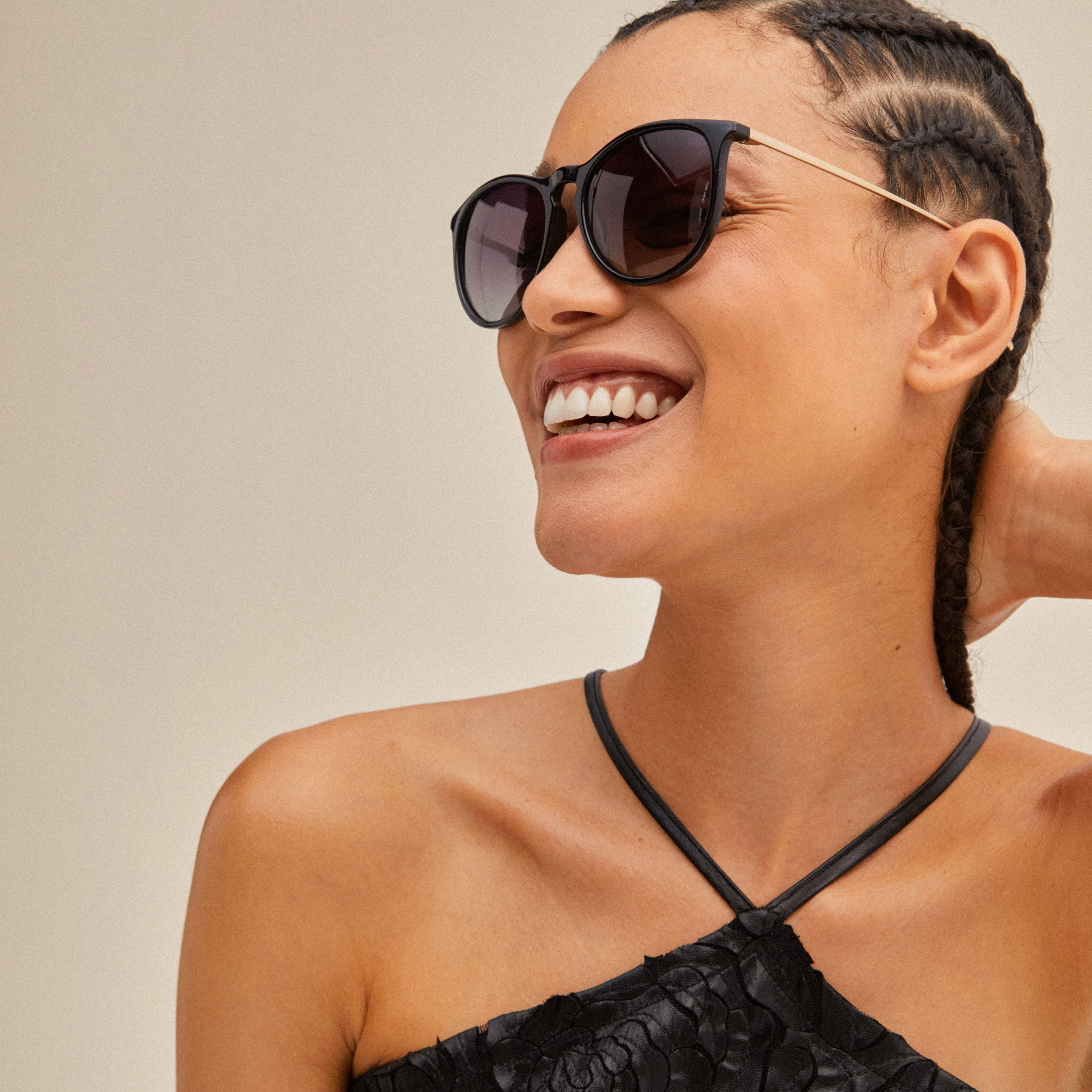 VANILLE sunglasses black/gold featuring stylish metal temples and soft rounded lenses, worn by a smiling woman. Perfect for a trendy, classy look.
