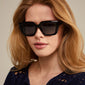Woman wearing JOGLI sunglasses black/gold with oversized design and gold details, showcasing Pilgrim's blend of trend and sustainability.