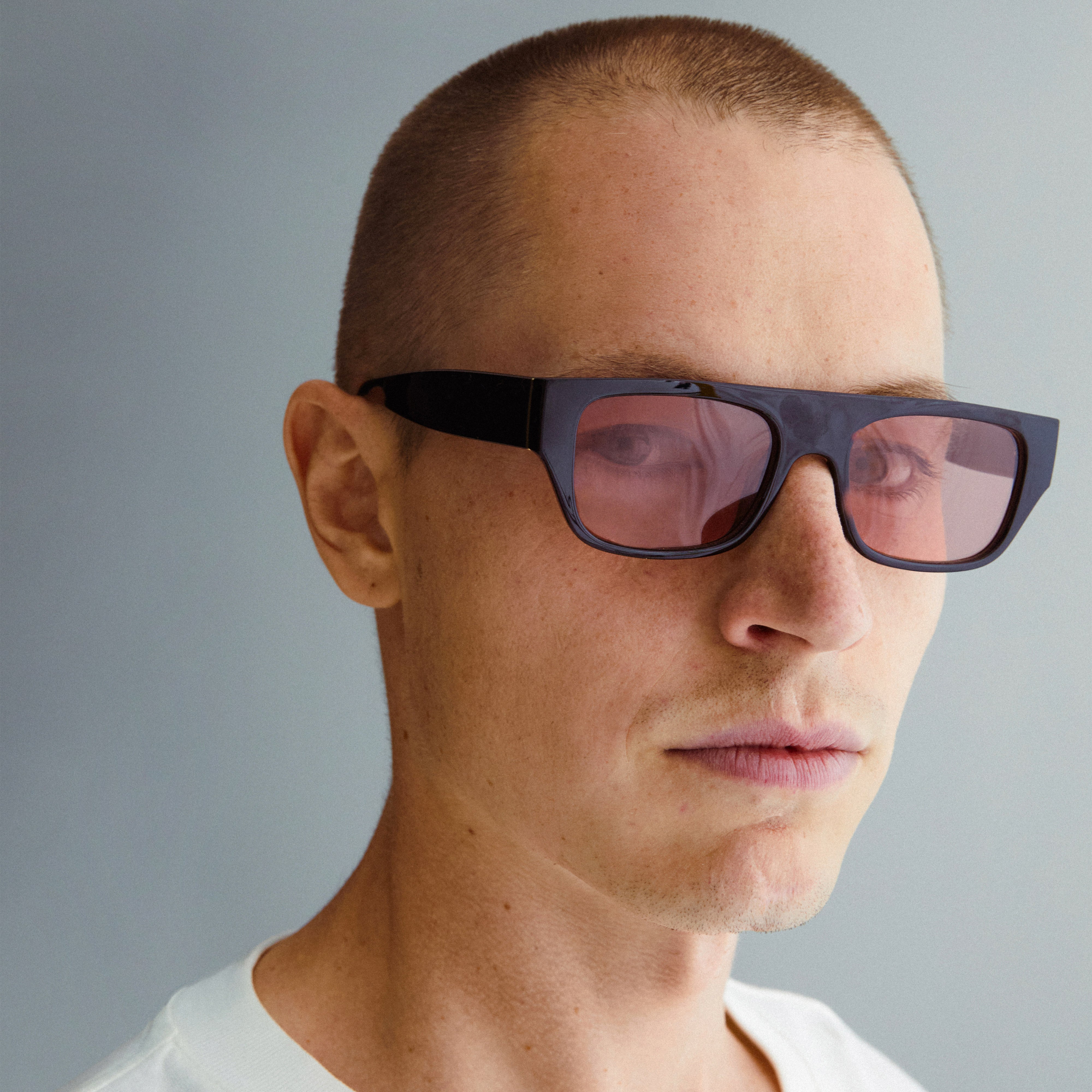 ENIEL sunglasses in black with gold detail, featuring trendy orange lenses, worn by a man, embodying classic style with a modern twist.
